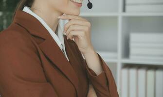 jong vriendelijk operator vrouw middel met headsets werken in een telefoontje centrum. foto