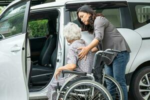 verzorger helpen en ondersteuning Aziatisch ouderen vrouw zittend Aan rolstoel bereiden krijgen naar haar auto naar reizen in vakantie. foto
