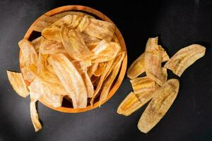 banaan chips met een zoet en zout smaak gemaakt van gebakken rauw bananen in een houten schaal. traditioneel snacks foto