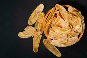 banaan chips met een zoet en zout smaak gemaakt van gebakken rauw bananen in een houten schaal. traditioneel snacks foto