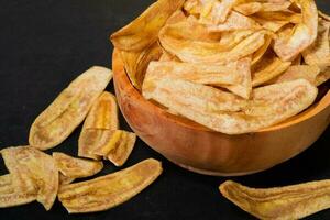 banaan chips met een zoet en zout smaak gemaakt van gebakken rauw bananen in een houten schaal. traditioneel snacks foto