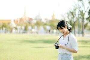 portret van Aziatisch vrouw reiziger gebruik makend van camera. Azië zomer toerisme vakantie concept met de groots paleis in een achtergrond Bij Bangkok, Thailand foto