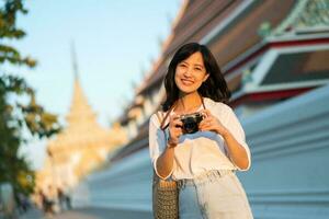 portret van Aziatisch vrouw reiziger gebruik makend van camera Bij straat van Bangkok, Thailand. Azië zomer toerisme vakantie concept foto