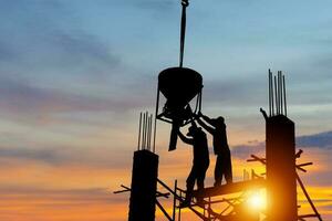 silhouet van arbeider team Bij gebouw plaats met knipsel pad, bouw plaats Bij zonsondergang in avond tijd foto