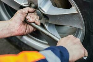 auto wiel vervanging. Zelfbediening band passend concept. gebruik makend van een wiel moersleutel naar twist de wiel noten. foto