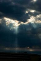 bedreigend dramatisch lucht met donker wolken en stralen van zomer zon foto