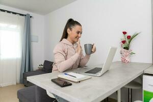 gelukkig vrouw golvend hand- naar laptop gedurende video telefoontje foto