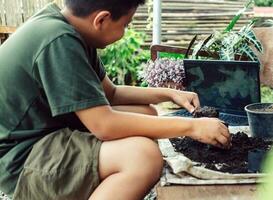 jongen leert naar toenemen bloemen in potten door online onderwijs. scheppen bodem in potten naar bereiden planten voor aanplant vrije tijd activiteiten concept foto