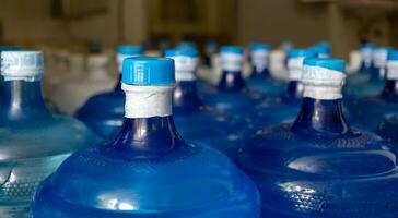 de blauw water gallon met drinken water heeft geweest verzegeld met een plastic zegel in de drinken water fabriek naar wacht voor levering foto