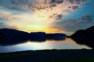 fjord met zonsondergang en verlichte wolken in de lucht. visie van bergen en fjord foto