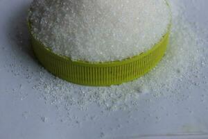 suiker in een groen plastic pet Aan een wit achtergrond dichtbij omhoog foto