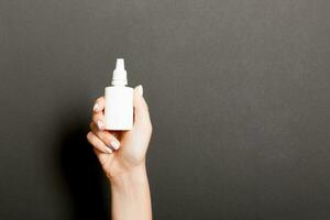 vrouw handen houden geneeskunde fles neus- verstuiven Aan zwart achtergrond isolatie foto