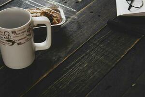 banaan taart Aan een zwart houten tafel met Notitie boek, bril, en koffie mokken. foto