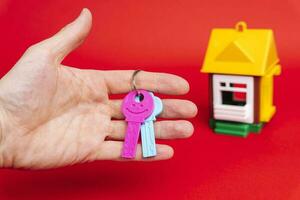 man's hand- Holding de sleutel naar de huis, en een model- van de huis foto