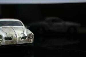 een model- van een oud klassiek haveloos auto Aan glanzend zwart glas. detailopname foto