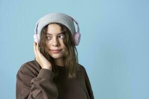 een schattig Europese tiener- meisje in modieus gebreid hoed luistert naar muziek- met draadloze hoofdtelefoons foto