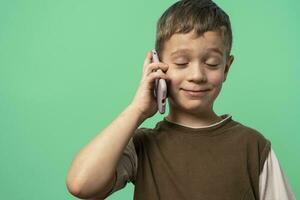 grappig Kaukasisch jongen is pratend Aan de telefoon met zijn ogen Gesloten met genoegen foto