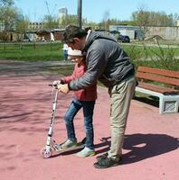 Sankt petersburg Rusland - 05 01 2023 vader schijven zijn dochter Aan een scooter Aan een bijhouden in de park in de val. foto