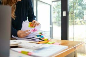 zakenvrouw handen werken Aan stapels van papier documenten naar zoeken en recensie documenten opgestapeld Aan tafel voordat Bezig met verzenden hen naar bord van bestuurders naar gebruik correct documenten in vergadering met zakenman foto