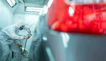 auto monteur in auto verstuiven kamer gebruik een verstuiven mondstuk geïnjecteerd naar de kant van de auto lichaam met zorg naar creëren schoonheid dat mengsels met de origineel kleur van de auto. foto