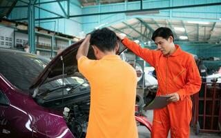 beide van auto mechanica zijn inspecteren de motor van een klanten auto wezen gebracht in voor reparatie Bij een garage. foto