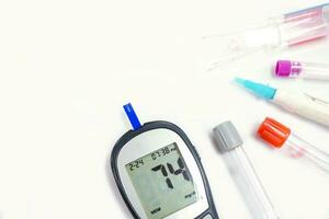 top visie glucose meter machine en getallen van glucose in de bloed tonen Aan scherm met vel controleren, bloed buis, naald- pen, en medisch capillair glas buizen isoleren Aan wit achtergrond. foto