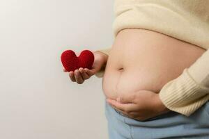 een zwaarlijvigheid gebruik makend van meten plakband naar tonen de echt maat. mollig dik vrouw gebruik makend van meten plakband Bij buik. echt grootte vrouw na gaf geboorte naar baby, echt huid met rimpels en littekens. foto