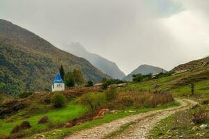 aarde weg naar regenachtig bergen. kapel in eer van de dood. in eer van de icoon van de moeder van god, de herstel van de dood kapel. irafsky wijk, stoer-digora dorp. Rusland. foto