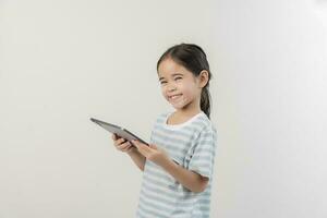 glimlachen weinig meisje stichtend en Holding een tablet foto