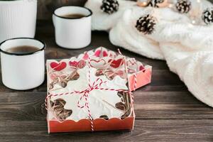 peperkoek koekjes met sneeuwvlokvormig suikerglazuur in dozen en twee mokken van thee Aan een houten tafel. Kerstmis traktatie. detailopname. kopiëren ruimte foto