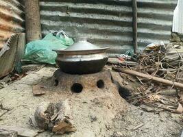 landelijk keuken. traditioneel fornuizen gebruikt door Bewoners in landelijk Indië, gemaakt van klei, aangewakkerd met hout, Koken voedsel Aan bodem fornuis met droog doorbladert en hout in dorp foto