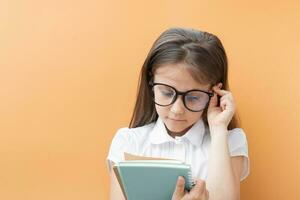 een 7 jaar oud meisje in bril met notebooks. kinderen opleiding, aan het leren concept foto