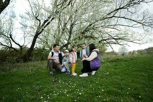 familie met drie kinderen in voorjaar weide Aan de achtergrond van een bloeiend boom. foto