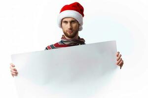 knap Mens in een Kerstmis hoed met wit mockup poster Kerstmis licht achtergrond foto