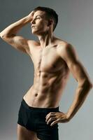 bodybuilder geschiktheid Mens met een opgewonden torso hand- achter hoofd grijs achtergrond model- bijgesneden visie foto