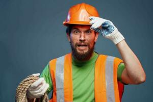 Mens in werk uniform oranje verf touw in handen moeilijk werk bijgesneden visie foto