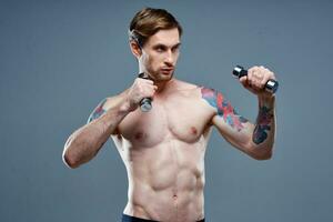 sexy atletisch mannen met halters Aan grijs achtergrond en biceps druk op tatoeages foto