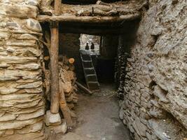 een oud huis met oude modder aangekoekt steen muren met een klein houten trappenhuis en twee kippen in de dorp van kagbeni in mustang in de Nepal Himalaya. foto