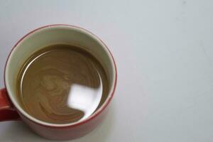 dichtbij omhoog heet cappuccino koffie in een rood kop geïsoleerd Aan een wit achtergrond foto