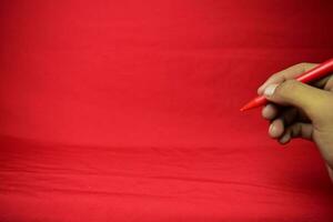 Mens hand- met rood pen schrijven Aan rood achtergrond foto