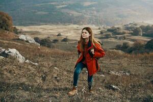 vrouw wandelaar in jasje laarzen met rugzak reizen in bergen landschap foto
