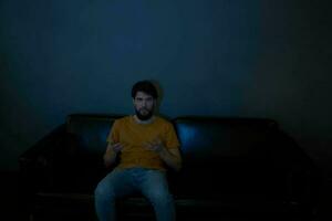 een Mens zit Aan een sofa binnenshuis en horloges TV voorkant visie foto