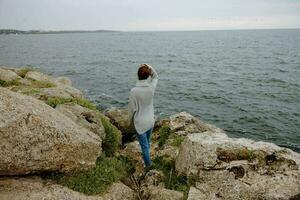 portret van een vrouw strand toerisme bewolkt weer steen kust ontspanning concept foto