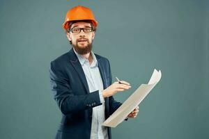 mannetje ingenieur met blauwdrukken in de handen van een oranje moeilijk hoed industrie professioneel foto