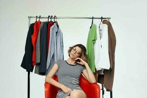 mooi vrouw zittend Aan de rood stoel in de buurt de garderobe geïsoleerd achtergrond foto