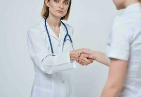professioneel dokter vrouw schudt hand- van een vrouw geduldig Aan een licht achtergrond foto