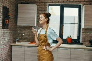 mooi vrouw in een bruin schort keuken interieur modern stijl glas van water foto