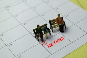 miniatuur mensen thingking over planning voor pensioen doelwit of stoppen ze functie. geïsoleerd kalender achtergrond foto