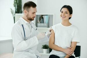 de dokter injecteert de vaccin in de patiënten schouder ziekenhuis en beschermend handschoenen infectie foto