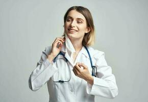 vrouw dokter in medisch masker Holding handen in de buurt gezicht blauw stethoscoop bijgesneden visie foto